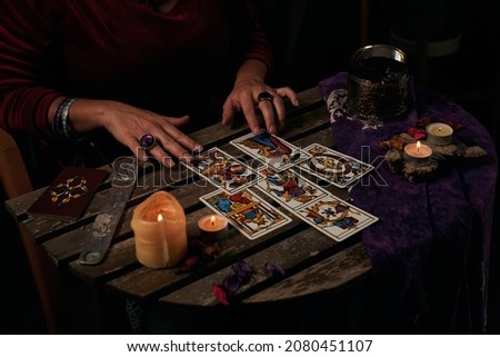 Pythoness reads tarot cards on a table with candles