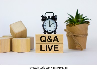 Q and A, questions and answers live symbol. Concept words 'Q and A live' on wooden blocks on a beautiful white background. Black alarm clock and house plant. Business and Q and A live concept.