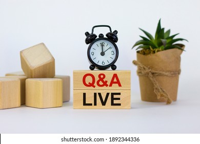 Q and A, questions and answers live symbol. Concept words 'Q and A live' on wooden blocks on a beautiful white background. Black alarm clock and house plant. Business and Q and A live concept.