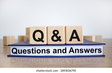 Q and A, questions and answers symbol. Concept words 'Q and A questions and answers' on wooden cubes on book on a beautiful white background. Business and Q and A concept.
