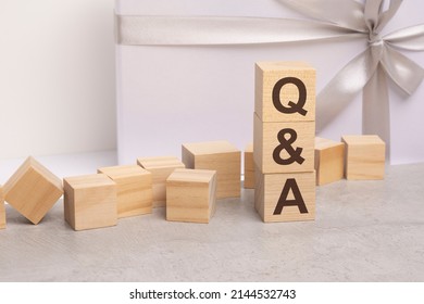 qa - letters on wooden cubes. concept on white gift box background