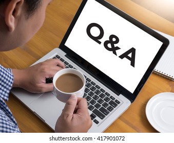 Q&A - Question and Answer Businessman at work. Close-up top view of man working on laptop while sitting at the wooden desk , coffee