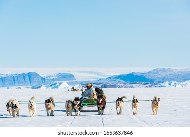 QAANAAQ, GREENLAND - MAY 5, 2014: Musher And His Dogs On A Dog Sledge Trip.