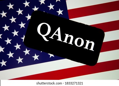 QAnon Organisation Logo Seen On The Smartphone Which Is Placed On USA Flag. Concept For QAnon Or Q Anon, A Deep State Conspiracy Theory. 