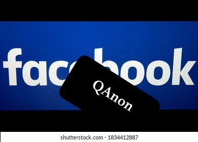 QAnon Vs FACEBOOK. QAnon Organization Logo Seen On The Smartphone Which Is Placed On Facebook Logos. Concept For Ban Of QAnon On Social Media. Amsterdam / Netherlands - 09.09.2020