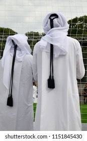 Qatari Men In Traditional Clothes Watch The Game On A Football Stadium