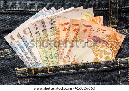 Qatari Riyals in the back pocket of blue jeans