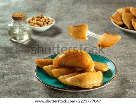 Qatayef is a type of Arabian Oriental sweet made during the month of Ramadan, and typically stuffed with cheese. These desserts are baked and served with hot sweet syrup.  Grey background
