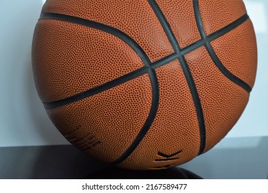 Qingdao, Shandong, China - June 12 2022: Round Brown Orange Faux Leather Rubber Basketball With Black Lines Closeup On The Bumpy Texture Perfect For Sports Games Marketing Advertising And Retail.