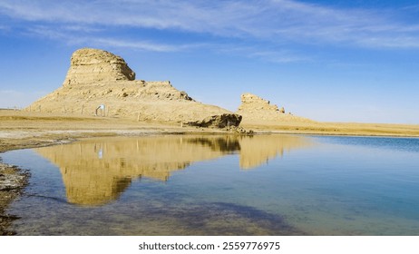 Qinghai Water Yardang Scenery showcases unique rock formations and serene waters under a clear blue sky - Powered by Shutterstock