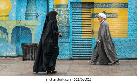 Qom, Iran - May 2019: Iranian Man And Woman In Black Dress Walking In A Street In The Sacred City Of Qom