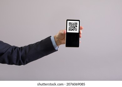 QR code on the smartphone screen, which is held in the hands of a man. The concept of mandatory vaccination of a person confirmed by a QR code.