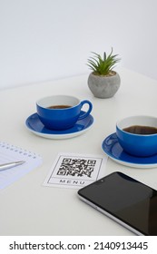 QR Code For Online Menu Service At Table In Restaurant New Contactless Technology Lifestyle Protect. Phone And Blue Mugs On The Table