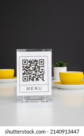 QR code for online menu service at table in restaurant New contactless technology lifestyle protect. Yellow mugs on a white table.