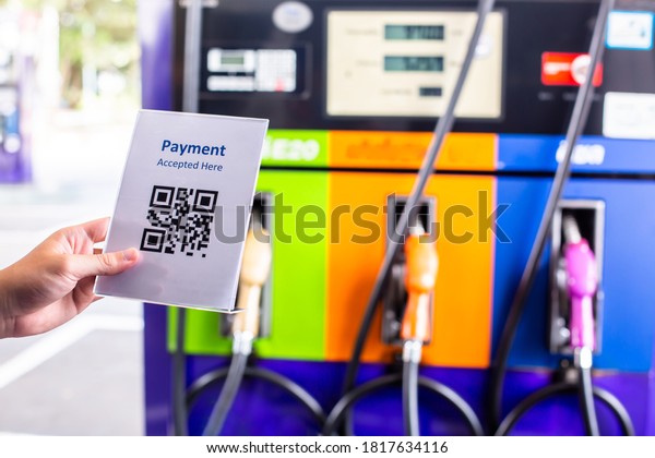 QR code payment tag with blurry gas pump nozzles\
in a service station. The concept of cashless technology or digital\
payment for fuel energy.