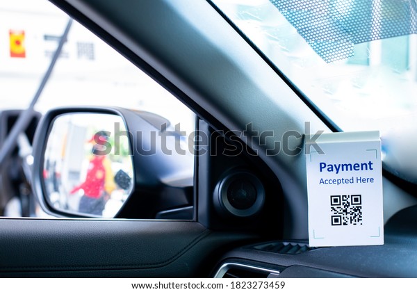 QR code payment tag with blurry image on\
wing mirror of staff  in \
 gas station. The concept of cashless\
technology or digital payment for fuel\
energy.