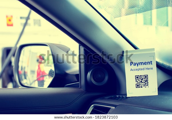 QR code payment tag with blurry image on\
wing mirror of staff  in \
 gas station. The concept of cashless\
technology or digital payment for fuel\
energy.