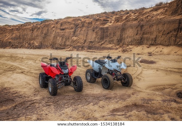 Quad ATV all terrain vehicle, parked on beach, red\
and white motor bikes ready for action, with summer sun on bright\
day, outdoor extreme activity adrenaline sport, racing, San Felipe,\
Mexico
