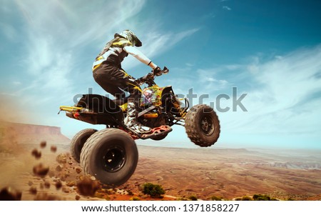 Quad bike in dust cloud, sand quarry on background. ATV Rider in the action.