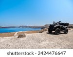 Quad bike parked on the seafront of the Akrotiri peninsula in the southwestern part of the island of Santorini with a view of the caldera. Travel, relaxation, adventure.