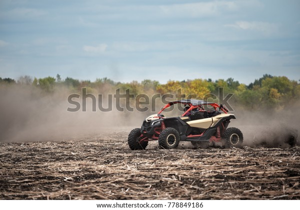 Quad bike in a plowed field. Dust from\
under the wheels symbolizes speed and\
movement.