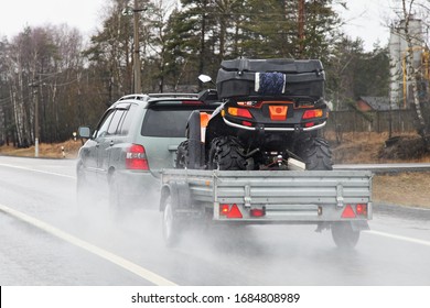 Quad bike transportation, a 4x4 car with a trailer on the suburban Highway