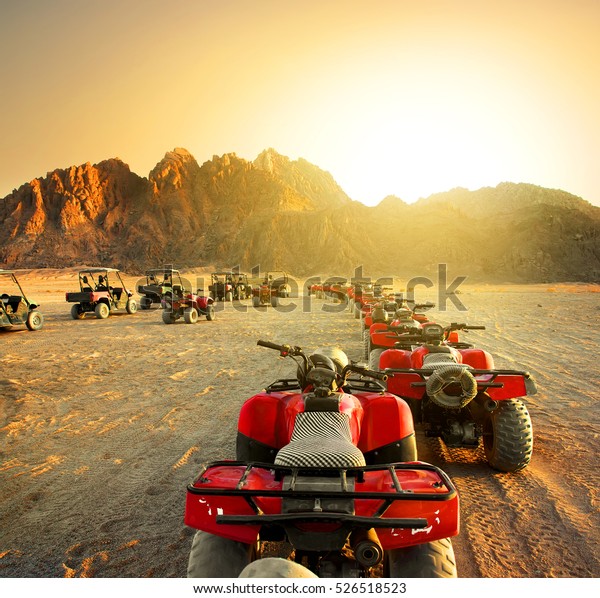 Quad bikes in desert at the\
sunset