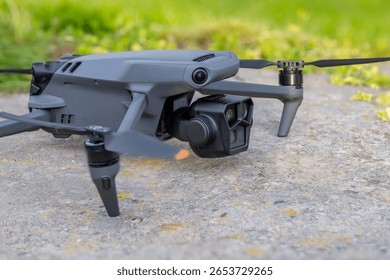 Quadcopter drone on flat dry concrete surface with green grass in the background