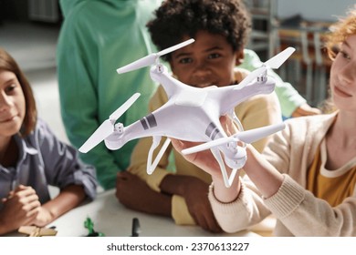 Quadcopter in hands of girl showing it to classmates in school