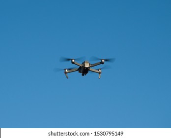 Quadcopter Or Quadrotor Helicopter Flying High At Blue Sky Background