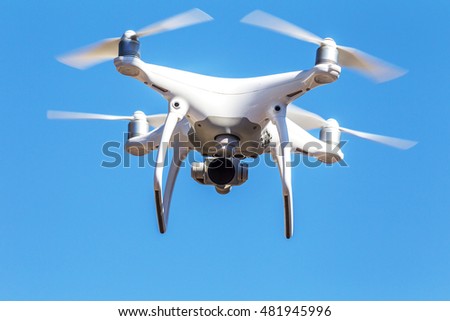 Quadrocopter unmanned camera hovers in bright blue sky above city on background of urban buildings Modern technology photo and video shooting bird's-eye view. Professional Carbon Quadrocopter with GPS