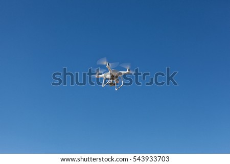 Quadrocopter unmanned camera hovers in bright blue sky