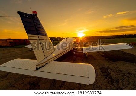 Quadruple aircraft parked at a private airfield. Rear view of a plane with a propeller on a sunset background.