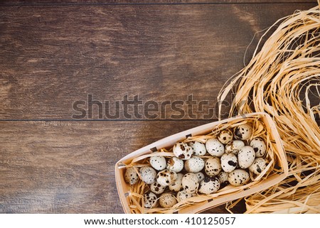Quail eggs in nest on a wooden table. Fresh chicken eggs on a wooden rustic background. Close up of organic eggs in egg carton box, nest box. Happy Easter and natural food background.
