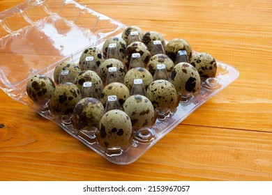 Quail eggs in a package on the table. Spotted quail eggs in a transparent box on a wooden background. Natural eco-friendly healthy products. Lots of fresh quail raw eggs in the egg tray. Close-up