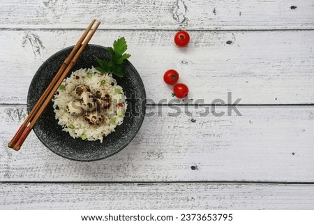 Quail eggs served in bowl with spicy rice on rustic wooden table. Asian cuisine. Copy space. Top view.
