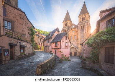 The quaint and charming medieval old town centre of the medieval French village Conques, Aveyron and Abbey Church of Sainte-Foy at sunset or sunrise in Occitanie, France.