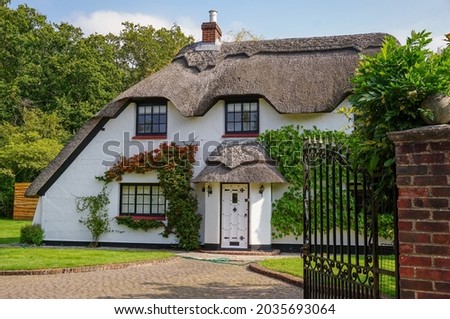 Quaint English cottage with traditional thatched roof. White country cottage in Hampshire England 