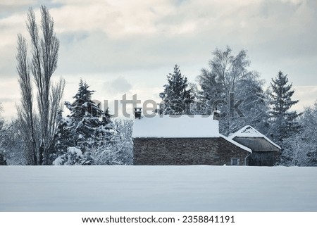 A quaint little house is situated in a vast winter landscape, blanketed in a thick layer of snow
