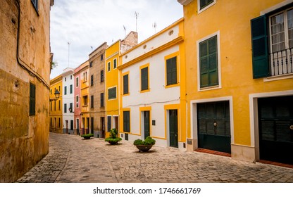 quaint narrow alley with colorful painted houses in the old town of ciutadella with vanishing point to the left side