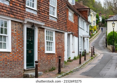 Quaint picturesque street with traditional terraced cottages winding uphill in Lewes, East Sussex with a walking figure in the background