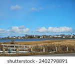 A quaint town seen in the distance from across the water with some clouds in the sky on an autumn day while standing in a street.