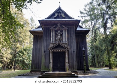 A quaint, wooden church stands surrounded by lush green trees in a tranquil forest environment. Its rustic architecture, with intricate carvings and aged wood, exudes a peaceful, spiritual ambiance. - Powered by Shutterstock