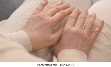 The quake hands of the old woman on her knees. Close-up. Top angle. Old shaking hands concept. Parkinson disease concept.
