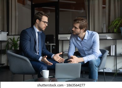 Qualified Broker Bank Manager Financial Advisor And Millennial Man Client Customer Discussing Terms Conditions Of Insurance Contract Loan Agreement Sitting By Laptop Screen On Meeting In Office Agency