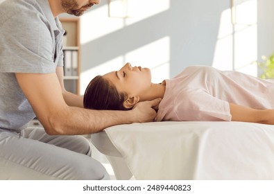 Qualified chiropractor, osteopath or manual therapist a young female patient to relax her tense shoulder muscles and to relieve neck pain. Chiropractic, osteopathy, therapy, treatment concept - Powered by Shutterstock