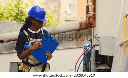 Qualified electrician filling out warranty contract for client to sign after maintenance work on air conditioner is finished. Proficient worker drafting cost of expenses on clipboard