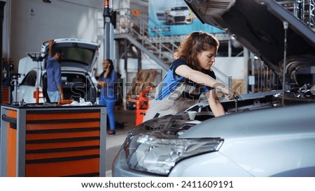 Qualified engineer in repair shop using torque wrench to tighten screws after opening car to check its parameters during maintenance. Expert using professional tool in garage to mend busted vehicle