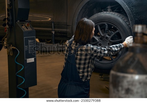 Qualified\
female mechanic replacing a tyre on a\
car