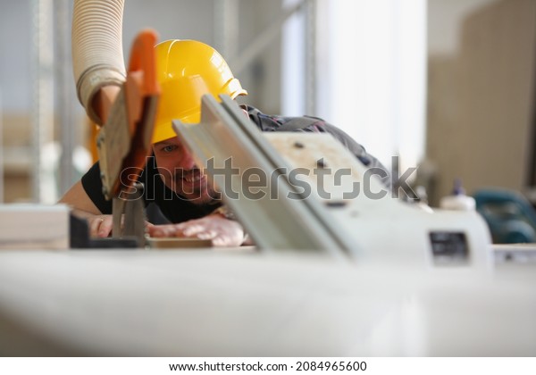 Qualified male worker using electric saw equipment\
for work with wood
